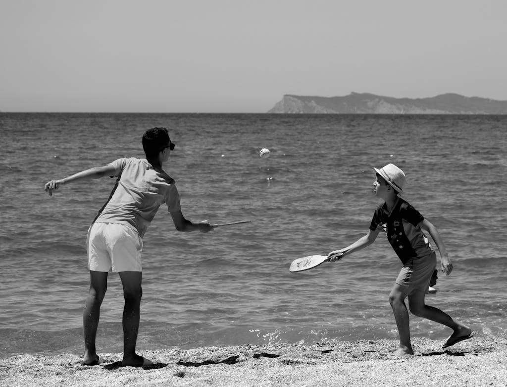 A Man and a Boy Playing Tennis Beside the Beach